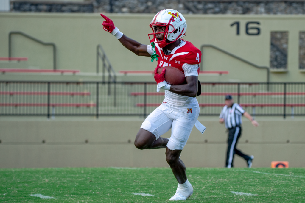 Destin Moore on the football field running a play for Virginia Military Institute. 