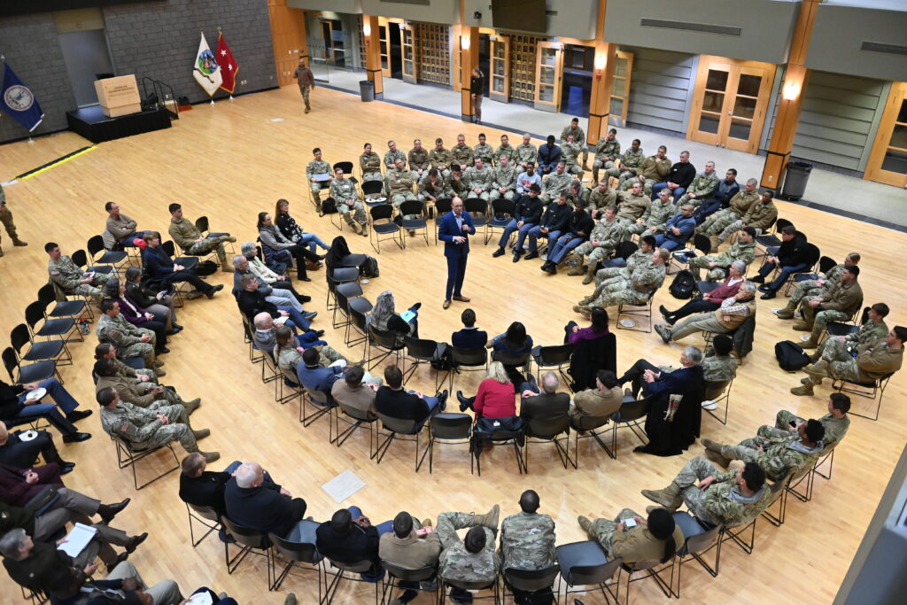 Cadets, faculty, and guests sit around a speaker during a debate in December 2025.