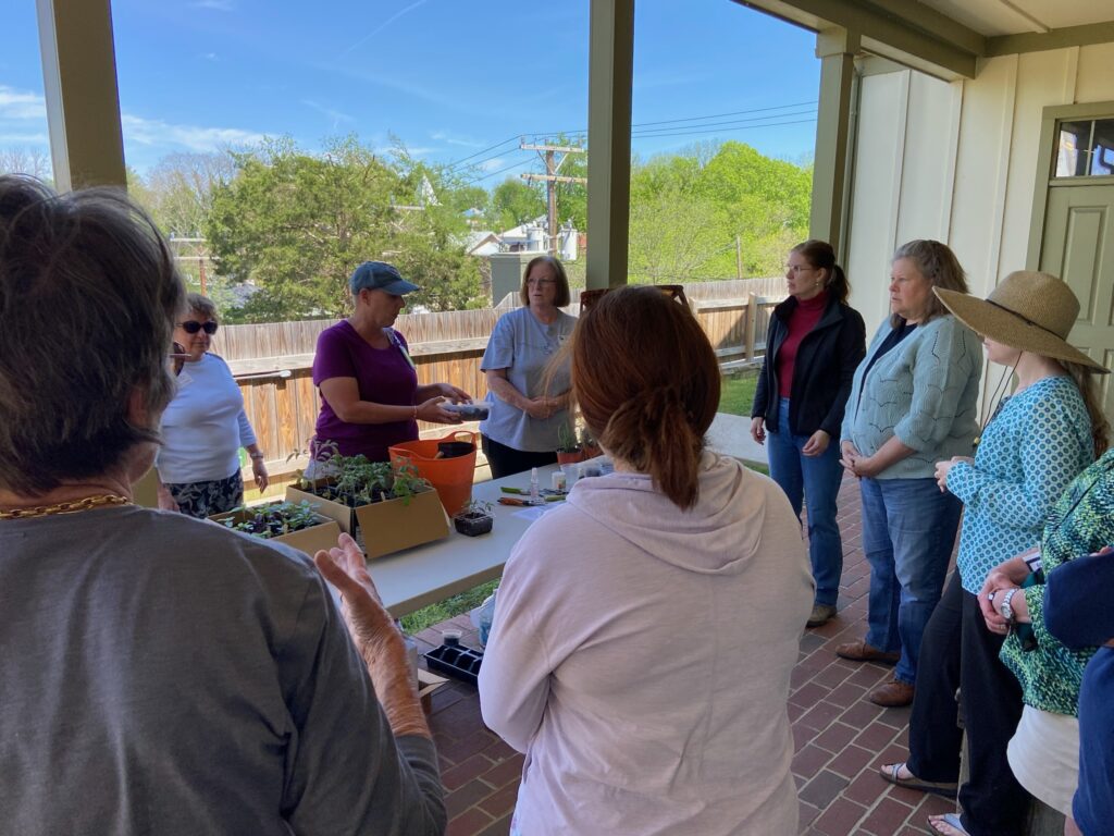 A group of event attendees observe while a Master Gardener shows soil.
