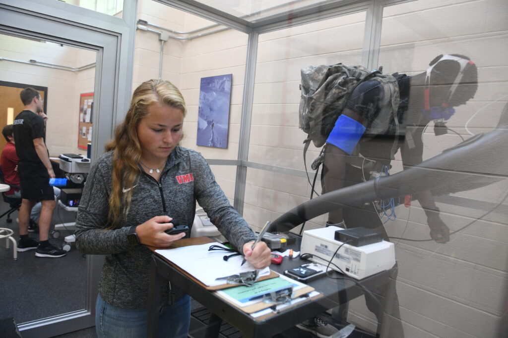 Caroline Lassalle ’25 investigating the effects of load carriage — a 65-pound ruck sack — on metabolism, ventilation, and tissue oxygenation at both sea level and stimulated altitude (above 12,000 feet), using a hypoxic chamber.